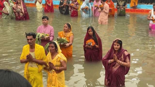 Large gathering of devotees observing Chhath Puja rituals along sacred riverbanks